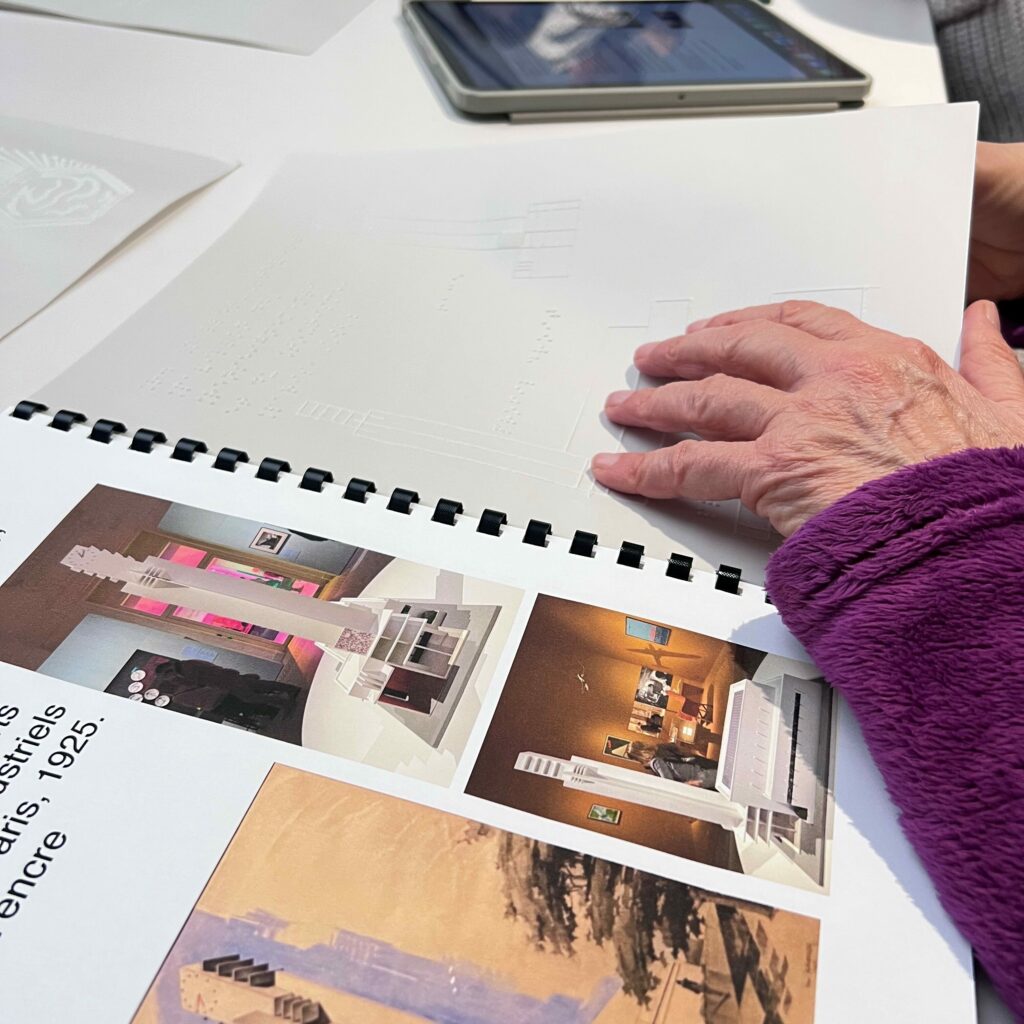 Photographie de livret tactile, sur la page de gauche les images de l'exposition et sur la page de droite le dessin tactile , un main l'explore